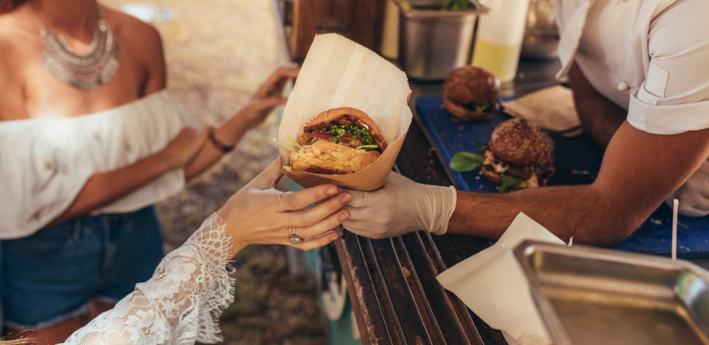 Pracownik food trucka podaje burgera klientce